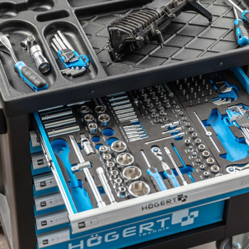 Komplet 9 kluczy Torx uniwersalnych w rozmiarach od T10 do T50, umieszczony w szufladzie narzędziowej. Klucze mają niebieskie uchwyty i są uporządkowane w matowej, czarnej wyściółce. W tle widoczne inne narzędzia na blacie.