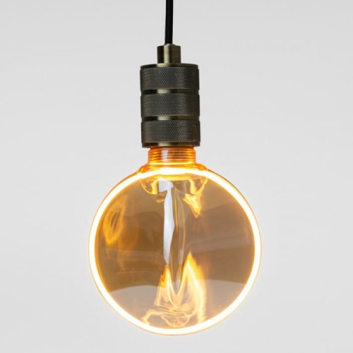 Żarówka LED E27 4W w bursztynowym kolorze, o średnicy 130 mm, emitująca ciepłe światło 1800K. Zawieszona na czarnym, metalowym mocowaniu, z wyraźnym efektem przezroczystości. Idealna do dekoracyjnych lamp.