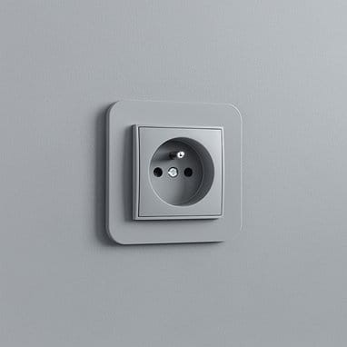 Potrójny łącznik Karlik MINI w kolorze szarym matowym, zamontowany na ścianie. Widoczne trzy otwory gniazda elektrycznego oraz prostokątna ramka. Produkt ma gładką teksturę i minimalistyczny design.