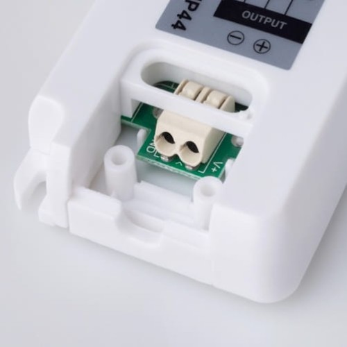 Zasilacz meblowy do taśm LED 24W 12V IP44 w białej obudowie. Widoczny port wyjściowy oraz wbudowany element elektroniczny. Kąt ujęcia zbliżenie na detal, ukazujący gniazdo przyłączeniowe.