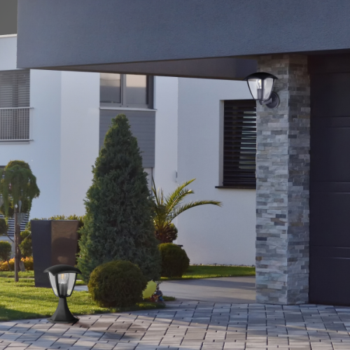 Lampa ogrodowa słupek IGMA o wysokości 29,5 cm w kolorze czarnym, z klasycznym designem, umieszczona na trawniku przed nowoczesnym domem, otoczona zielenią i dekoracyjnymi krzewami.