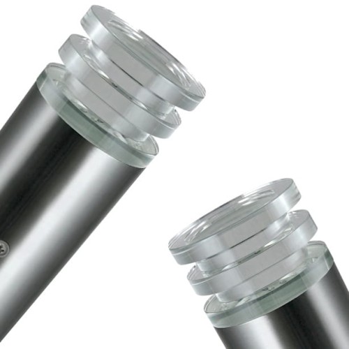 Kinkiet elewacyjny skośny CRYSTAL 6,5W w kolorze satynowym. Metalowa podstawa z przezroczystymi, szklanymi elementami u góry, w kształcie cylindrycznym. Detale okrągłych, szklanych kloszy i montażowa śruba. Umieszczony w pozycji stojącej.