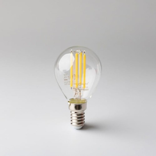 Żarówka LED filament KULKA E14 6W ciepła biała, z przezroczystą kulistą szklaną obudową, widoczne cztery żółte włókna filamentu. Ujęcie frontalne, produkt stoi na gładkim tle. Gwint E14 na dolnej części żarówki.