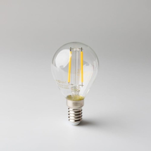 Żarówka LED filament KULKA E14 2W w ciepłej białej barwie, z przezroczystą szklaną obudową, widoczna żółta żarówka filamentowa, metalowy gwint E14, umieszczona na szarym tle, w pozycji stojącej.
