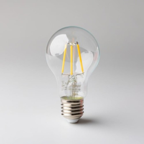 Żarówka LED filament E27 6W, ciepła biała, z przezroczystą szklaną bańką. Widoczne cztery żółte włókna LED w kształcie prostokątnym. U podstawy metalowy gwint E27, całość na szarym tle.