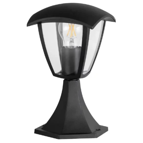 Lampa ogrodowa słupek Goldlux IGMA o wysokości 29,5 cm, w kolorze czarnym. Ma sześciokątną podstawę i osłonę z przezroczystego szkła, z widoczną żarówką wewnątrz. Ujęcie z przodu, pod kątem, ukazujące elegancki kształt i detale konstrukcji.