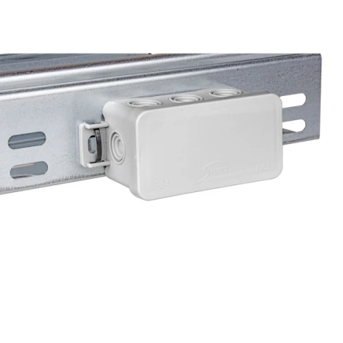 Puszka instalacyjna natynkowa NS8 w kolorze szarym, o wymiarach 45x85x40 mm, zamocowana na metalowym stelażu. Produkt posiada cztery otwory na przewody oraz oznaczenie IP54, co wskazuje na odporność na pył i wilgoć.
