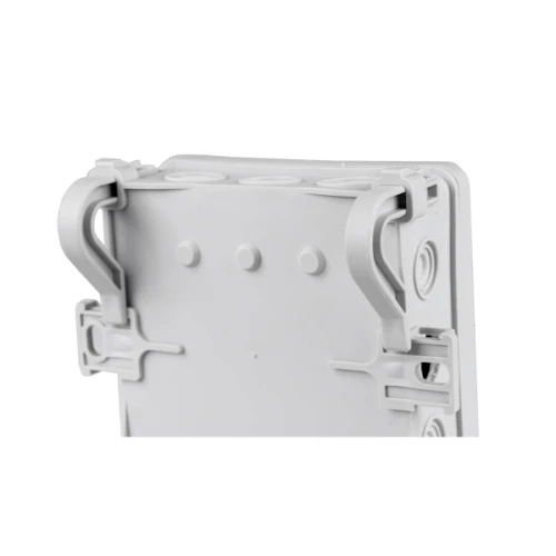 Puszka instalacyjna natynkowa NS6 w kolorze szarym, o wymiarach 85x85x40 mm, widoczna z boku. Zawiera dwa uchwyty montażowe oraz trzy otwory do podłączeń, wykonana z tworzywa sztucznego.