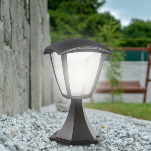 Lampa ogrodowa WENA 7W, wysokość 30 cm, w kolorze ciemnoszarym, z przezroczystym kloszem. Ujęcie z boku, umieszczona na szarej kamiennej nawierzchni, w tle widoczna zieleń i drewniane siedzisko.