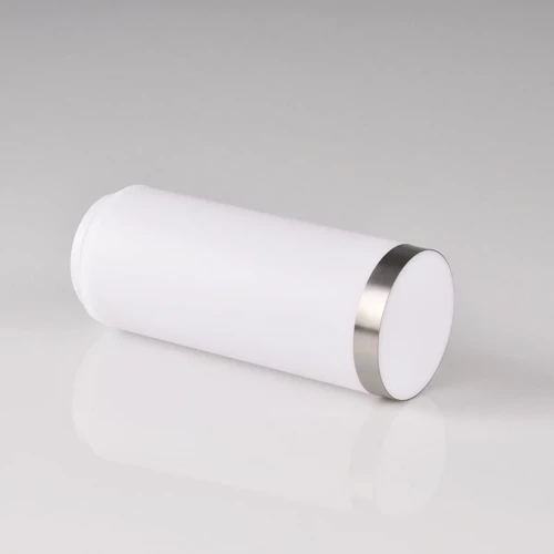Klosz do lampy LIVIA w kształcie cylindrycznym, wykonany z białego, matowego szkła, z metalowym, srebrnym obrzeżem u góry. Ułożony poziomo na gładkiej powierzchni, na jasnym tle.