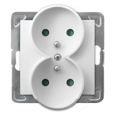 Podwójne gniazdo elektryczne Ospel Impresja z uziemieniem w kolorze białym. Gniazdo ma dwa okrągłe otwory z zielonymi oznaczeniami uziemienia oraz metalową ramkę montażową. Produkt montowany na ścianie.