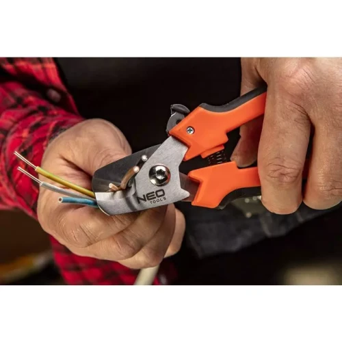 Obcinak do kabli miedzianych i aluminiowych Neo 01-510 w ręce użytkownika, z wyraźnym logo NEO TOOLS. Narzędzie ma metalową głowicę i pomarańczowe, ergonomiczne uchwyty. W tle widoczne są kolorowe przewody elektryczne.