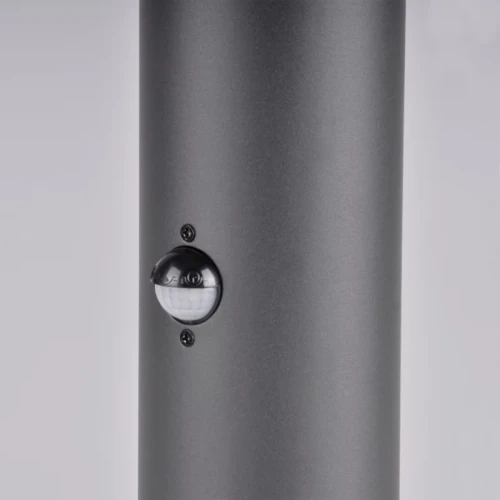 Lampa ogrodowa słupek DALLAS E27 o wysokości 44 cm w kolorze grafitowym, z widocznym czujnikiem ruchu i zmierzchu, umieszczonym na korpusie lampy. Wykonana z materiału odpornego na warunki atmosferyczne.