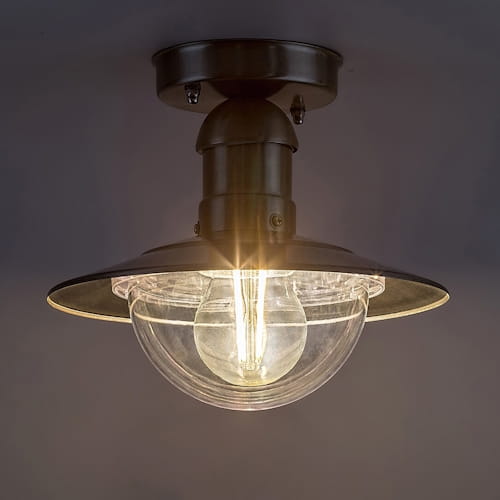 Oprawa sufitowa Oslo E27 1x60W w kolorze stal nierdzewna. Okrągła, przezroczysta kula z żarówką, metalowy klosz z szerokim rondem. Ujęcie z dołu, w jasnym otoczeniu, podkreślające elegancki design.