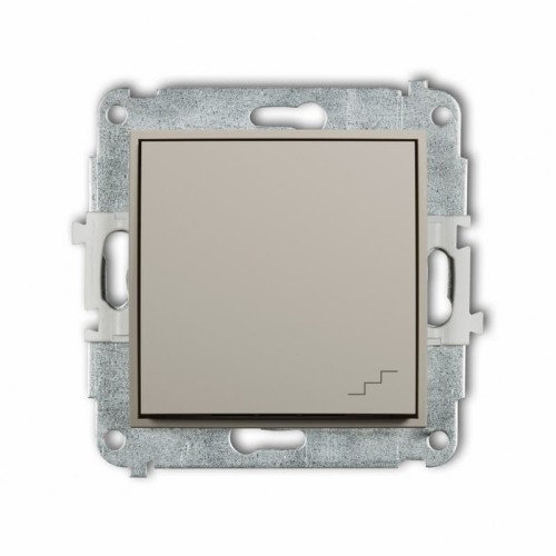 Łącznik schodowy Karlik MINI w kolorze taupe beżowym, kwadratowy, z metalową ramką montażową. Widoczny jest symbol schodów w dolnym rogu. Produkt zamontowany w ramie, pokazany z przodu, na jednolitym tle.